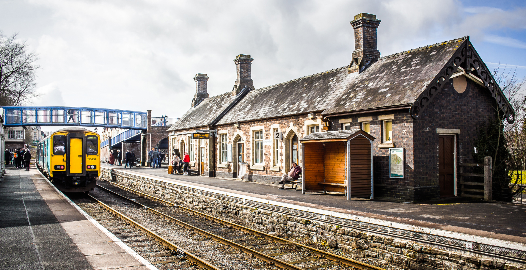 Image of Llandrindood Wells station with a train approaching the platform