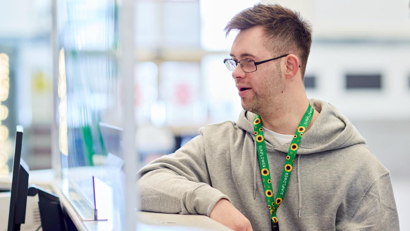 A passenger at a service desk talking to a member of TfW staff