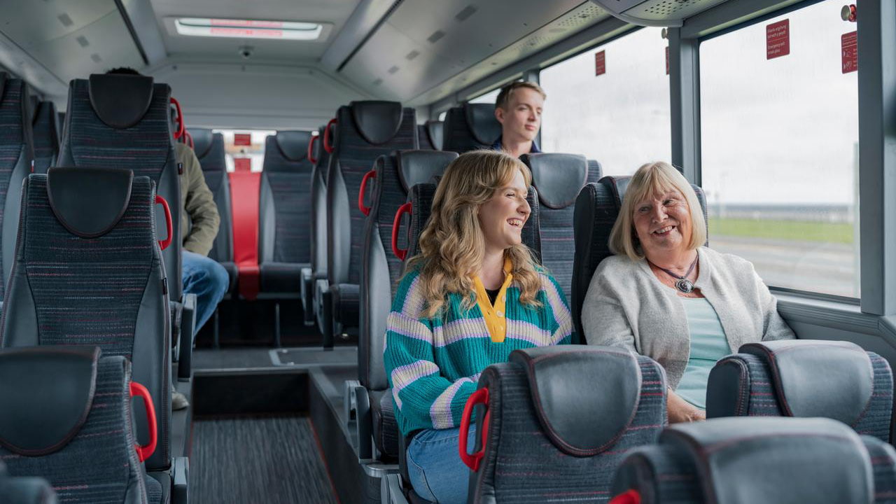 Two customers sitting next to each other chatting on a bus