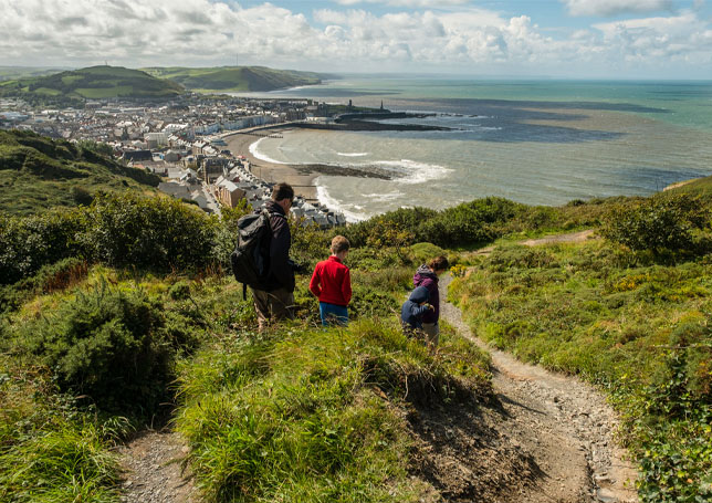 Three people walking down a hillside in Aberystwyth