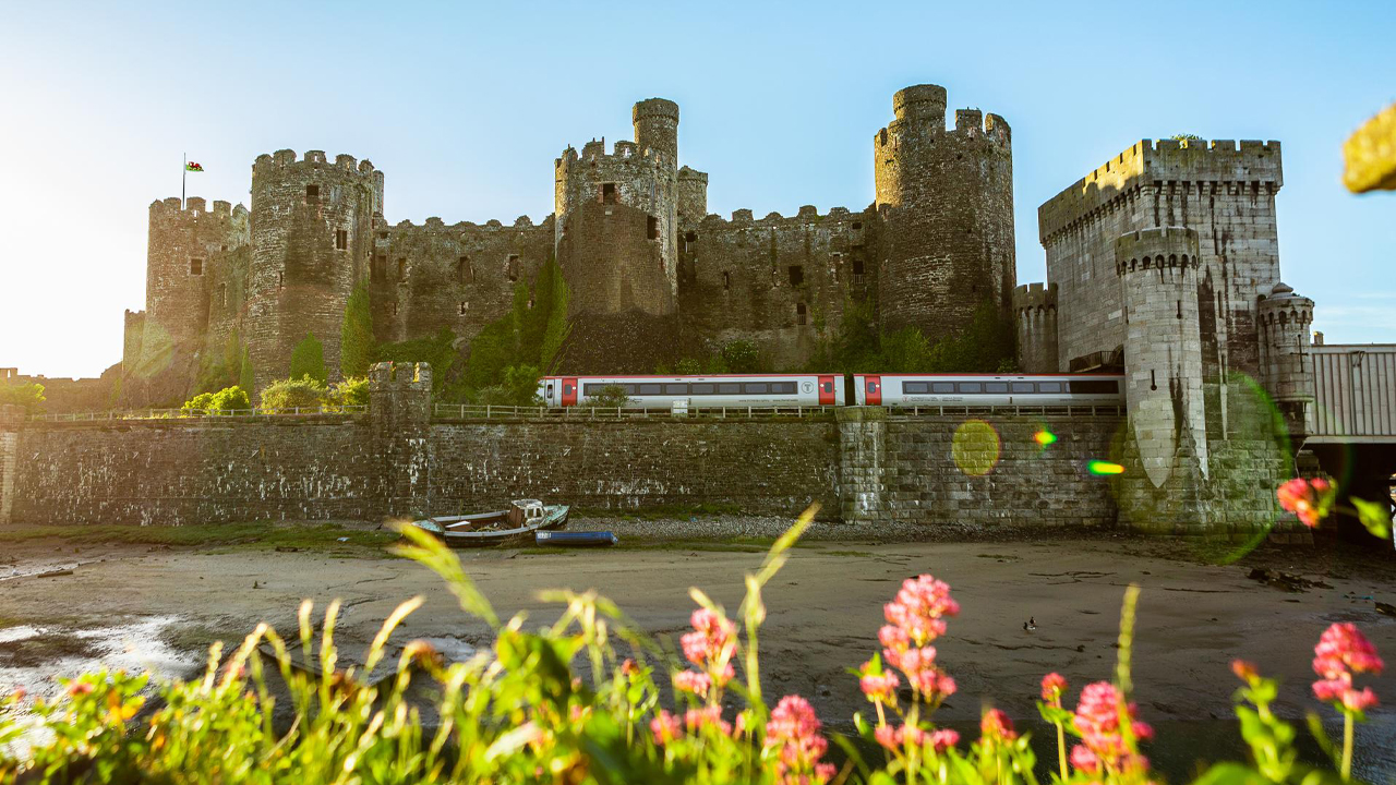 TfW train passing infront of a Cadw castle